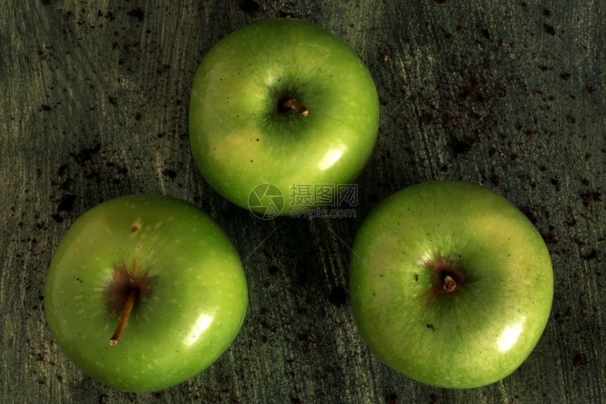 三个绿苹果在涂漆背景上被孤立图片