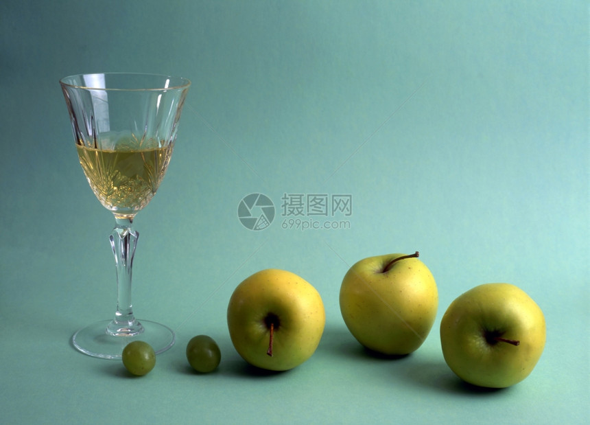 一杯白葡萄酒果子在绿色背景上分离图片