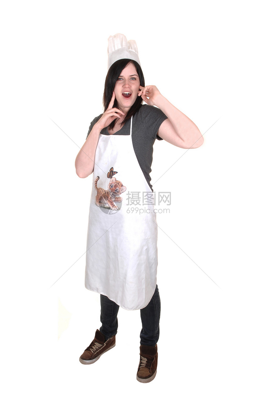 一个漂亮的年轻女子抚摸站着围裙黑头发和厨帽白背景图片