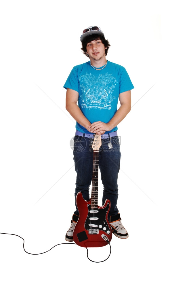 一个十几岁的男孩站在工作室拿着他的吉牛仔裤和蓝色毛衣图片