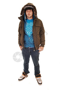 一个青少年站在工作室牛仔裤和蓝色毛衣帽子和冬夹克白色背景图片