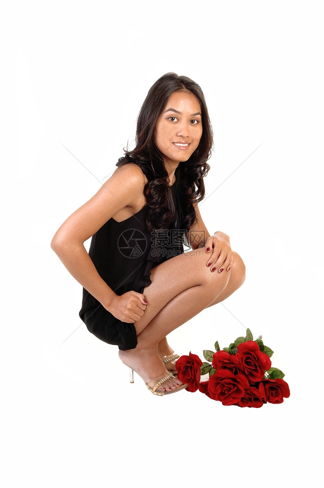 一个可爱的亚洲女孩穿着黑色的裙子和高跟鞋躺在地上脚穿着一束红玫瑰图片