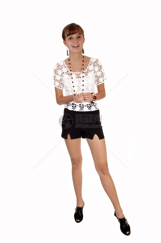 一个穿着高跟鞋黑短裤和白色上衣的可爱少女在工作室里带着她瘦的身体白背景图片