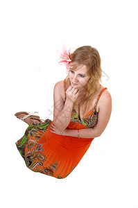 一个漂亮的少女坐在地板上做梦穿着彩色橙和粉红的百合花在她头发白色背景图片
