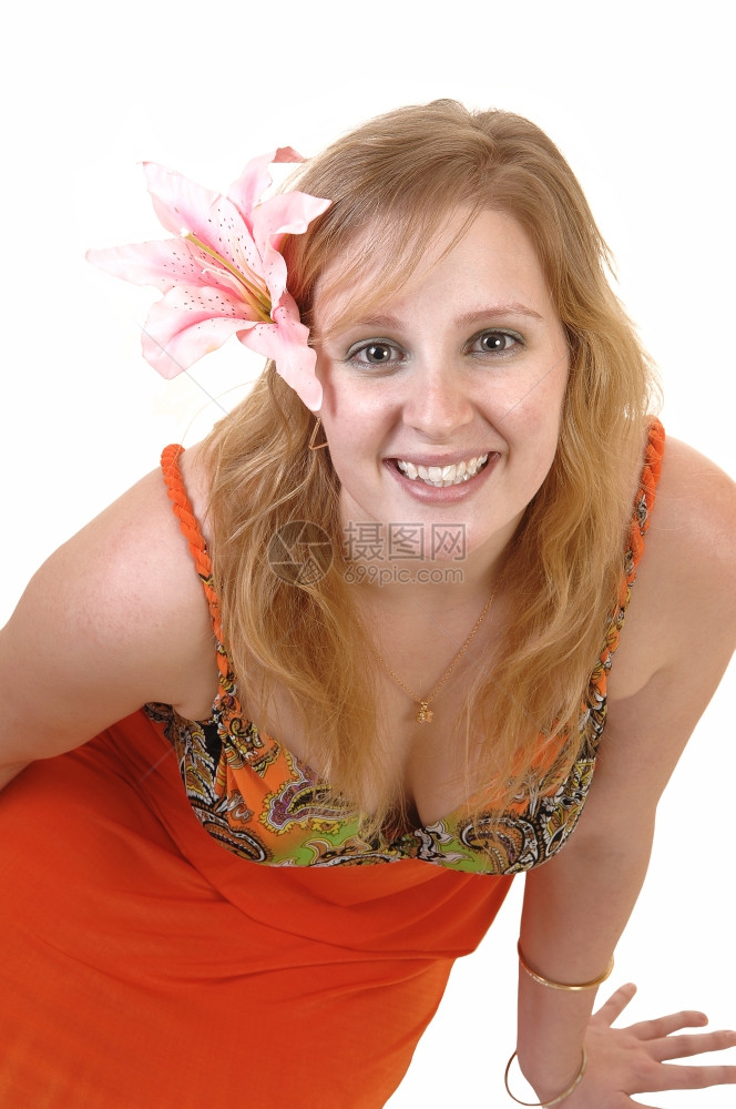 一个美丽的金发少女坐在地板上微笑镜头里发有粉红色的百合丽穿着彩色的橙裙子白背景图片