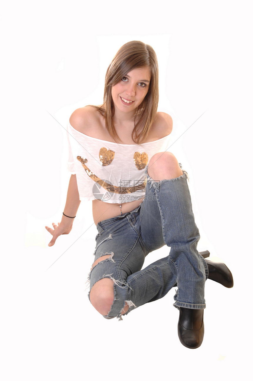 一个金发美女孩坐在地板上穿着破碎的牛仔裤和短图片