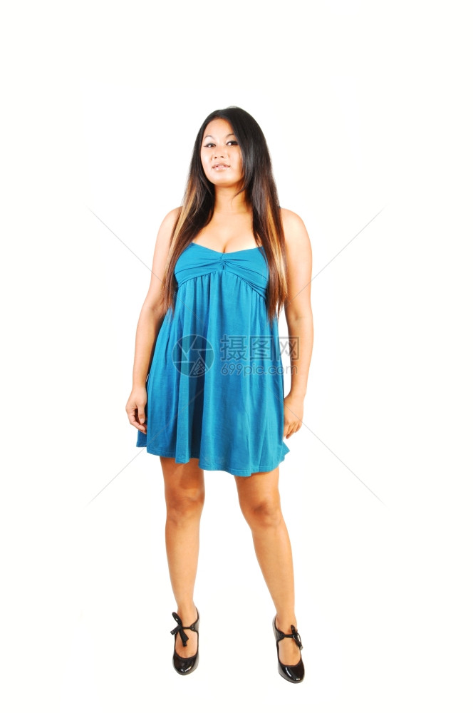 一个年轻的亚洲长发女郎穿着蓝裙子高跟鞋站在工作室里图片