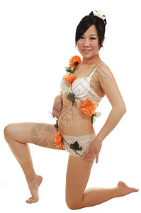 一位年轻的黏液亚洲女人穿着内衣跪在工作室里身上有漂亮的橙色花朵图片