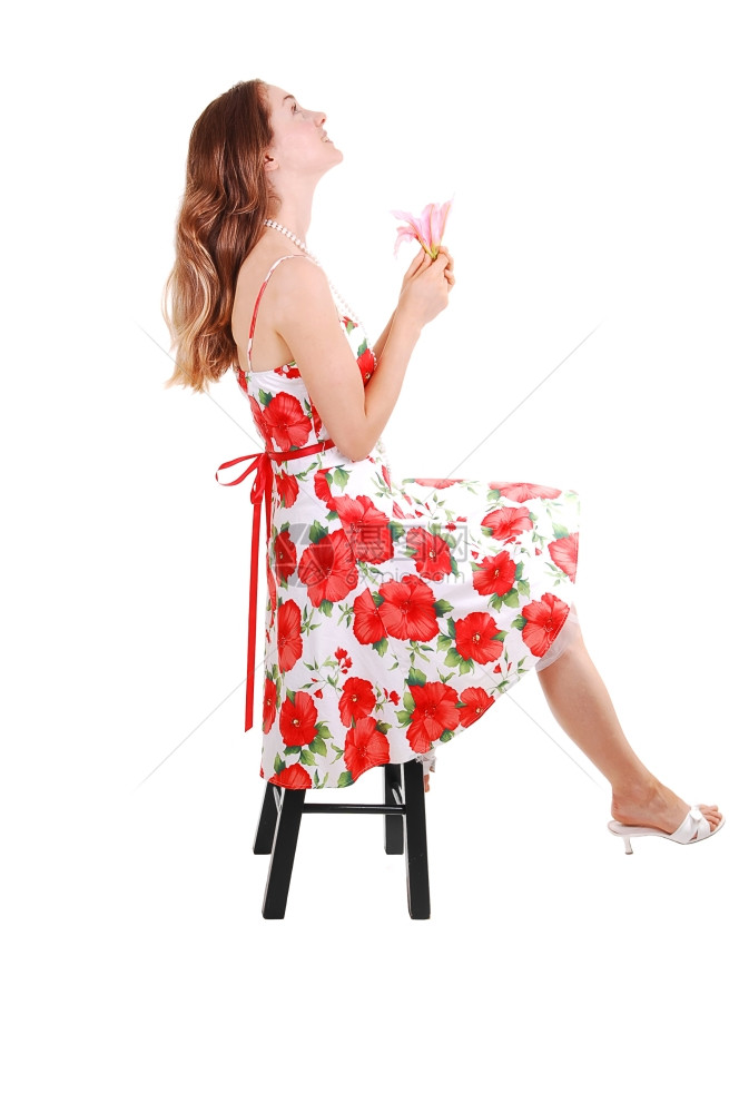 穿着高跟鞋的可爱年轻女人穿着漂亮的彩色裙子坐在工作室的椅子上图片