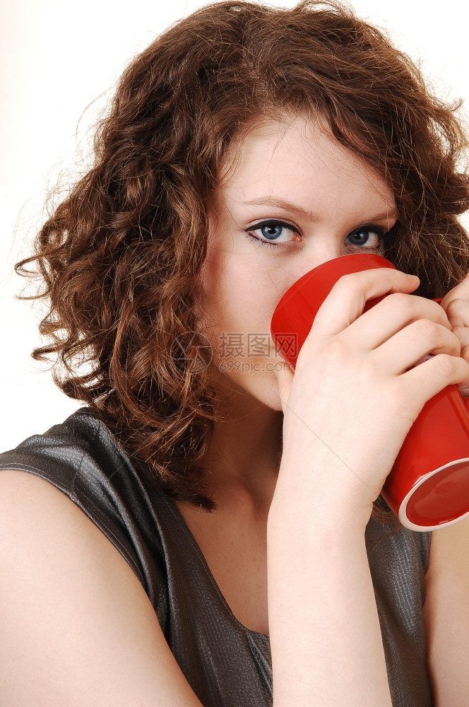 一个漂亮的年轻女人以一个大红杯咖啡来思考以白种人为背景图片