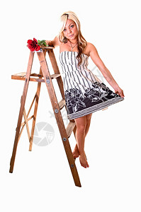 穿黑白裙子的漂亮女孩长的金发站在木制继梯上看着镜头图片
