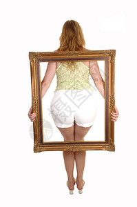 一个年轻金发女人的屁股在图片中显示白短裤高跟鞋和绿色顶部白背景图片
