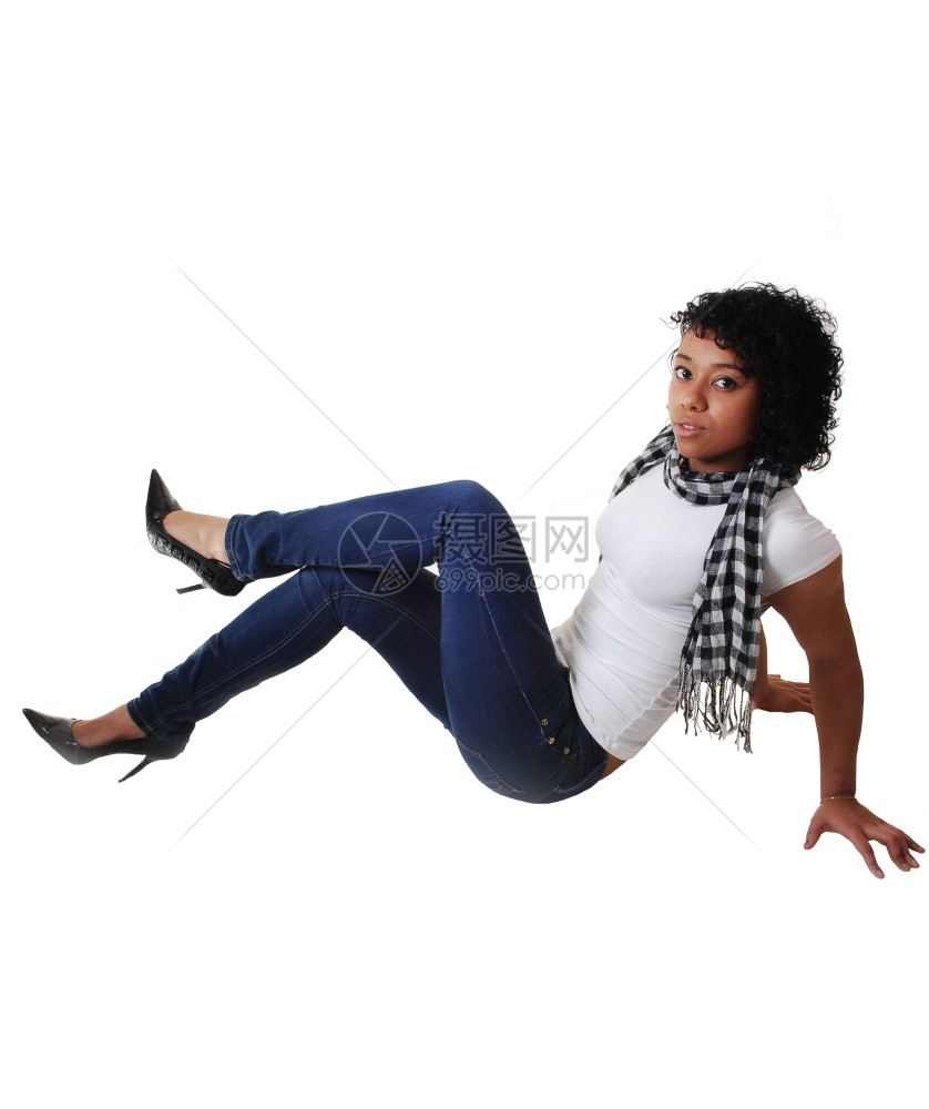 一个穿牛仔裤着白色上衣和高跟鞋的年轻美女坐在工作室的地板上挥舞着她瘦的身材图片