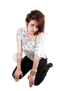 一个年轻少女跪在地上穿着黑色牛仔裤和靴子长棕色头发是白背景图片