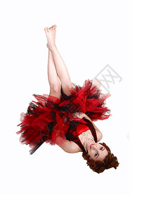 一个穿红黑色芭蕾装的年轻少女穿着红色黑芭蕾服躺在地上一个大木偶裙在工作室里做白底片背景图片