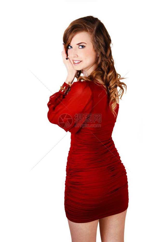 一个穿着红裙子留着长卷发的漂亮年轻女子站着xA对于白色背景从背面开始xA图片