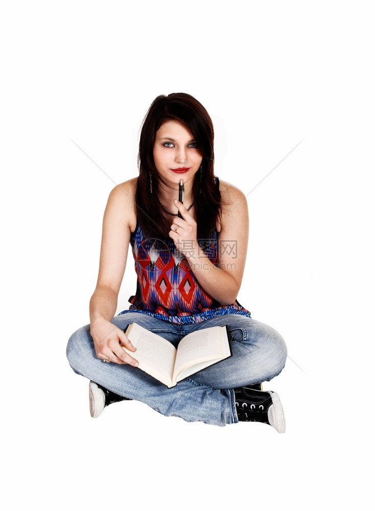 一个穿牛仔裤的年轻美女和一个多彩的上衣坐在地看书拿着笔图片