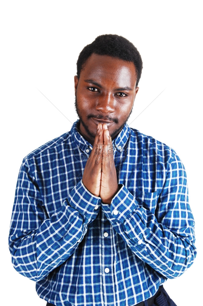 一个年轻的黑人站在白背景的隔离地带折叠双手祷告图片