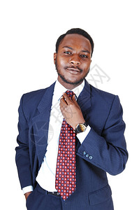 一个年轻的黑人商穿着蓝色西装领带修他的白色背景图片