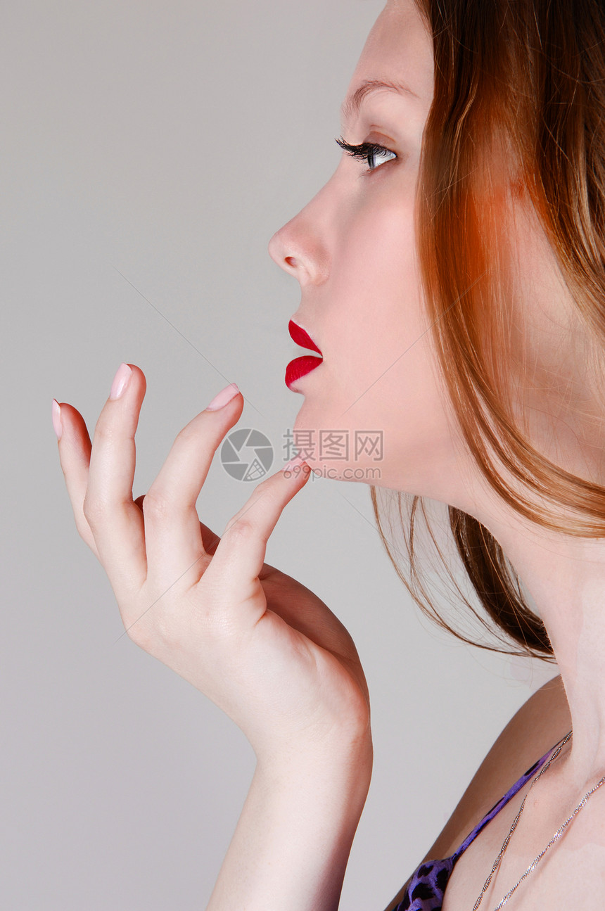一张近距离的肖像图片一位年轻女半张脸将她手握在下巴上被灰色的浅背景所隔离图片