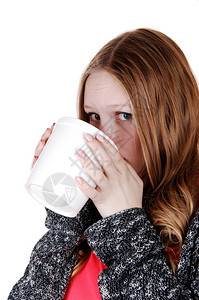 一个年轻可爱的少女站在一个白色背景的孤立中喝着大杯咖啡微笑在镜头中图片