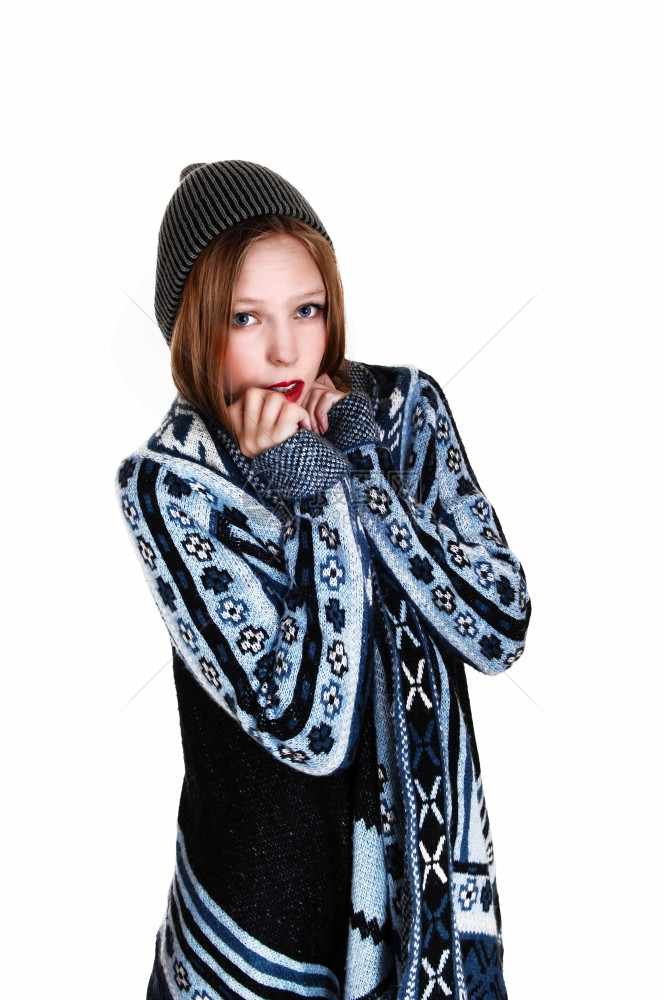 一个穿着蓝灰色毛衣和编织帽的年轻少女站立着因白背景被隔离图片