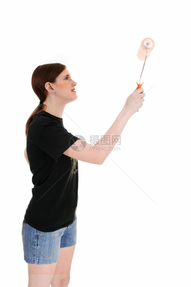 一个穿短裤的年轻女子拿着彩色滚机画墙壁孤立在白背景上图片