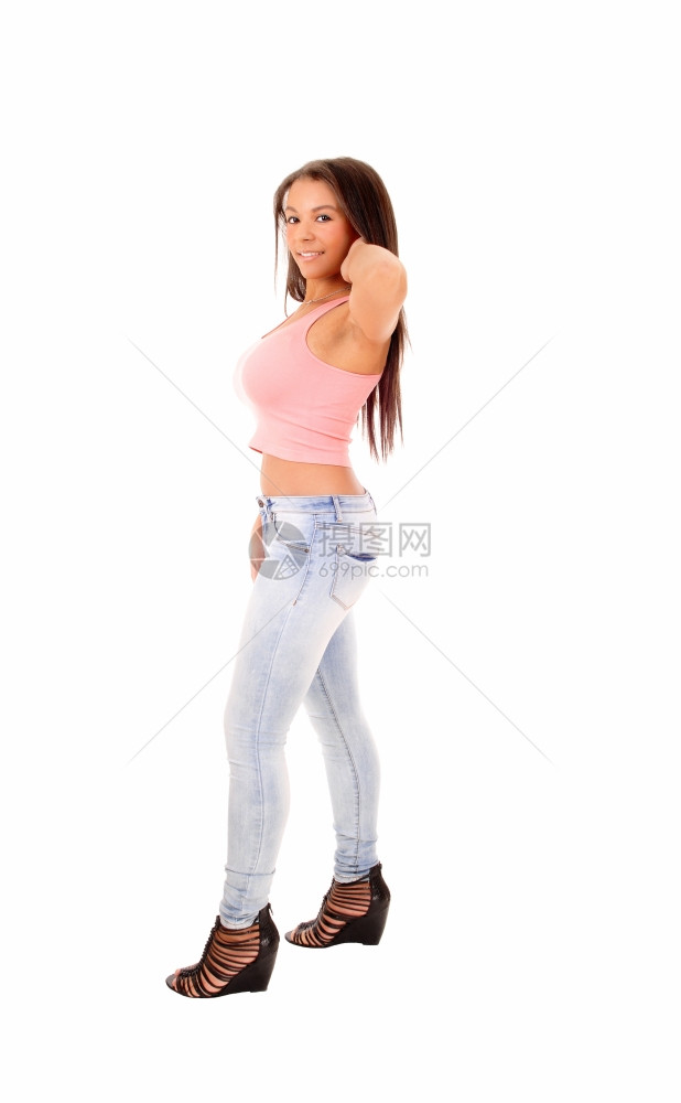 照片中一位年轻的少女站在牛仔裤和粉红色的顶端侧面和全身与白色背景隔绝图片