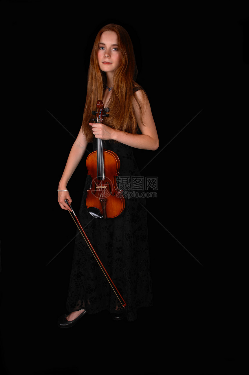 一位美女站在黑人背景面前拿着她的小提琴图片
