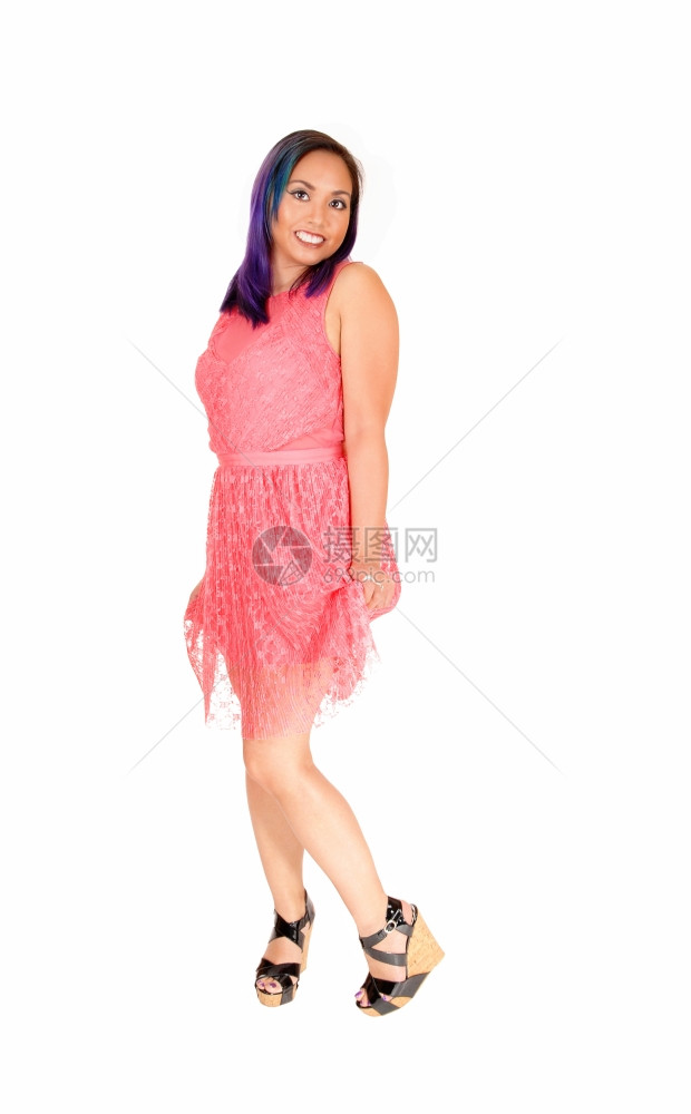 一个可爱的亚洲女人站在粉红色的裙子微笑看着相机孤立在白色背景图片