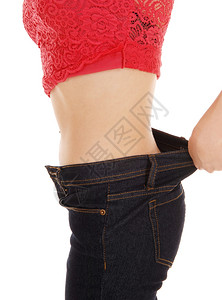 一位站在侧面的年轻女展示了她的牛仔裤体重减退身部位照片与白种背景隔绝图片