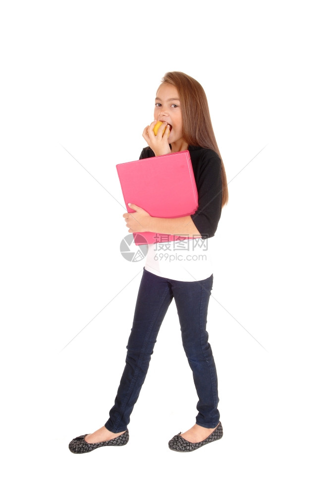 一个金发八岁的女孩站在白色背景拿着她的文件夹吃苹果图片