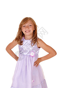一个穿着粉红色裙子的可爱年轻女孩手放在她的臀部站立不动的白色背景图片
