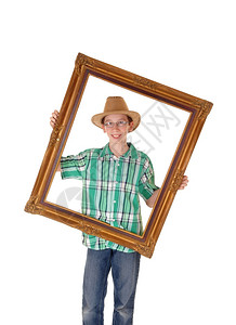 一个戴着帽子的年轻男孩在他面前拿着一幅画框孤立于白人背景图片