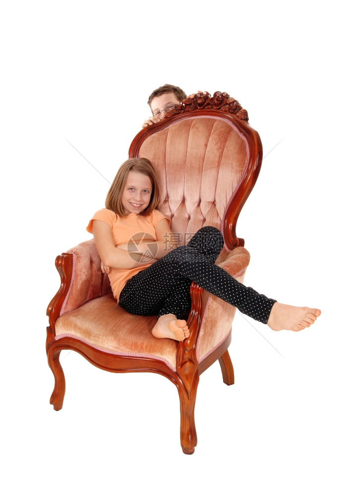 一个非常漂亮的年轻女孩坐在粉红色的扶手椅上与白种背景隔绝图片