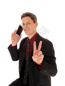 一个男人的近距离拍摄他的手机在耳朵上用两根手指签署胜利图片