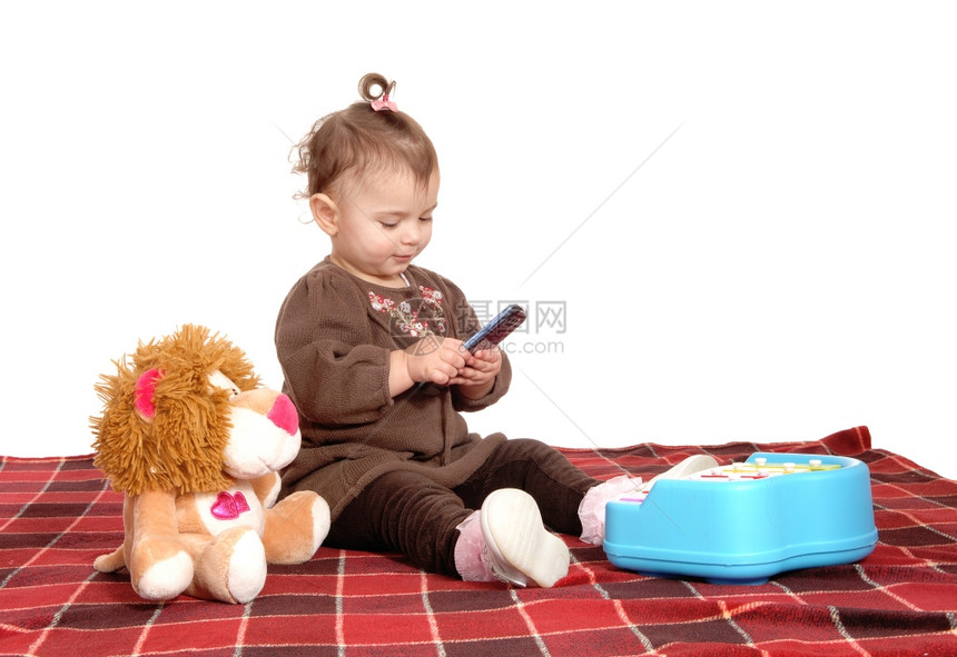 一个坐在地板上毯子拿着手机的可爱女婴图片