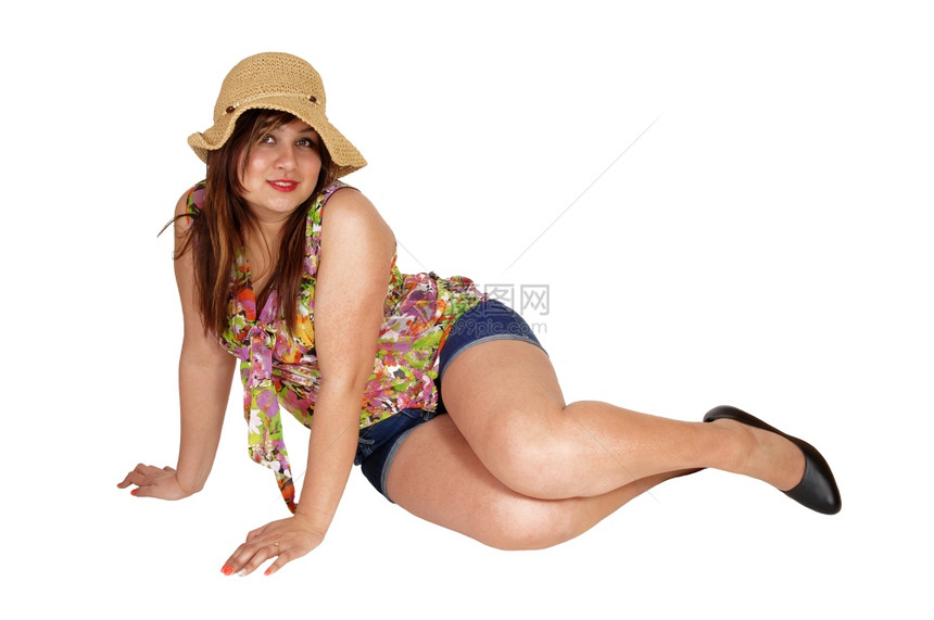 一个穿牛仔裤的年轻女子穿着草帽坐在地上白背景孤立无援图片