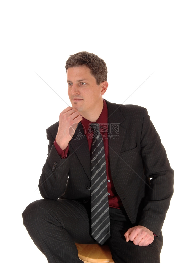 一位年轻的商人与世隔绝地坐在白种背景中手伸着下巴思考图片