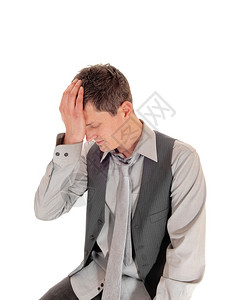 一个身着灰色衬衫领带和背心的年轻人坐在白地上图片
