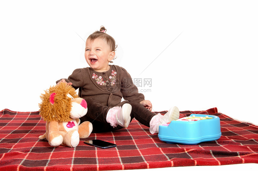 一个小女孩坐在地板上的毯子带着玩具耍图片