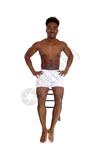 一个穿着白内衣坐在椅子上的非裔美国人男子因白背景而孤立无援图片