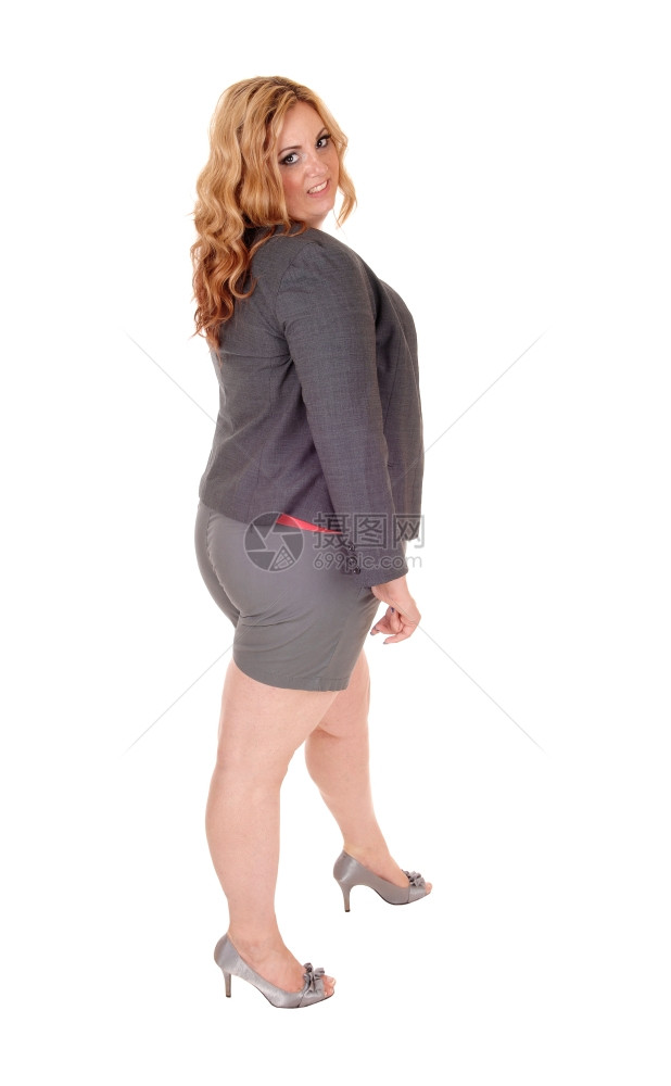 一个可爱的年轻又大女人独自站在白背景上穿着灰色夹克和短裤图片