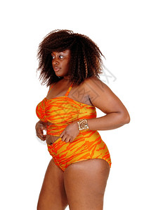 一位非裔美国年轻女子站在橙色比基尼的侧面白种背景孤立无援图片