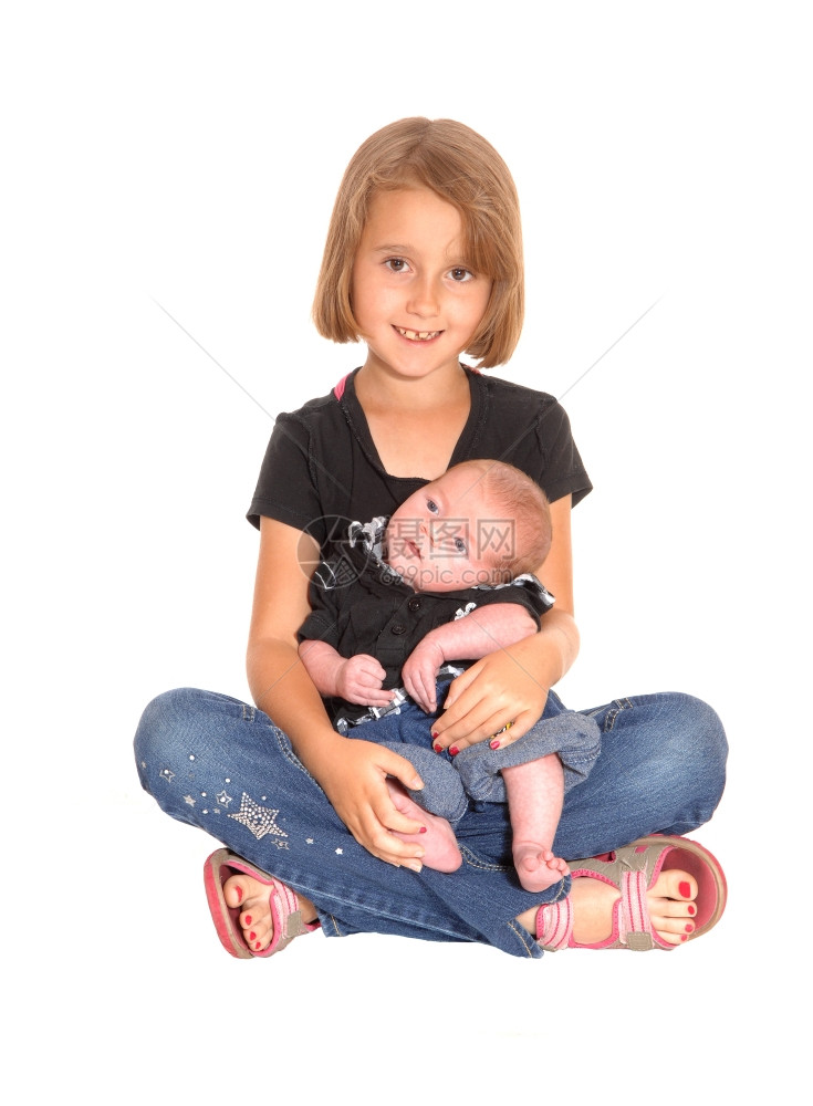 一个小女孩抱着她三个星期的哥在她大腿上坐地板图片