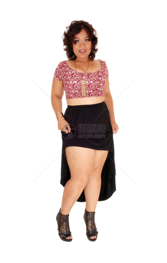 一个混杂种族的年轻女子站在一个黑色裙子的白背景中单独站着露出她的双腿图片