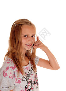 一个漂亮的年轻女孩金发站在侧面白色背景假装打电话图片
