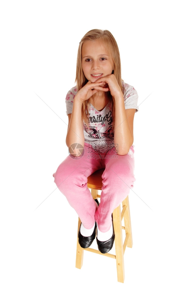一个金发的年轻女孩坐在椅子上双手下巴因白种背景被孤立图片