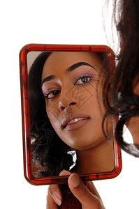一位非裔美籍年轻女望着镜子的影与白种背景隔绝图片
