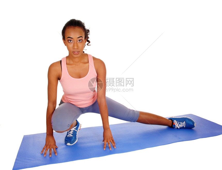 一个年轻的非裔美国女孩跪在瑜伽垫上伸展身体为了健康与白种背景隔绝图片